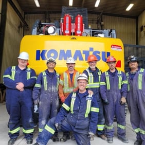 mining employees smiling and standing by machine protected with fire suppression