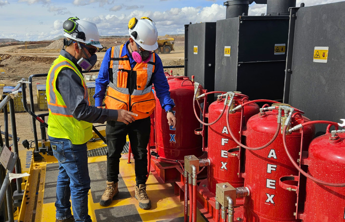 Technicians inspecting a fire suppression system on mining equipment